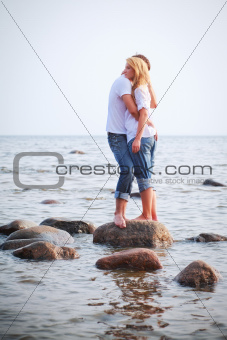 couple embrace on a stone in sea