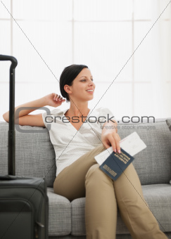 Dreaming young woman with bag holding passport and air ticket