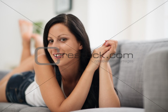Portrait of happy young woman laying on sofa