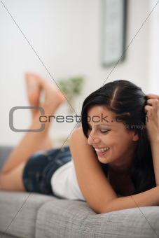 Portrait of laughing young woman laying on sofa