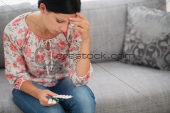 Concerned young woman looking on pack of pills
