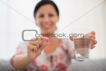 Closeup on female hands holding pink tablet and glass of water