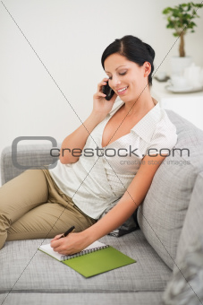 Woman speaking mobile and making notes