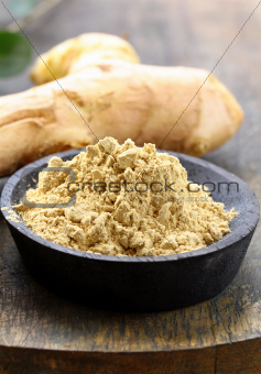 ground ginger (spice) and fresh on a wooden board