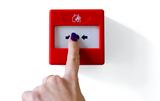Fire alarm trigger button being pressed by female finger