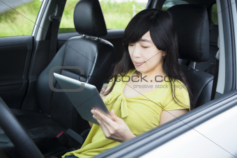 Young woman using tablet pc in the car 