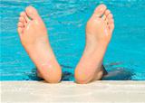 Man's feet with bright blue swimming pool background