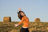 Beautiful woman open is arms  in a field with hay bales