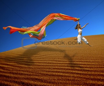 Rainbow woman jumping over the dunes