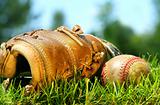 Old baseball glove and ball on the grass