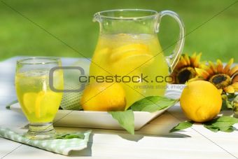 Pitcher of cool lemonade with glass on table
