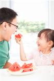 happy little girl with father eating fruits