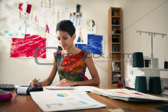 hispanic woman doing budget in fashion designer atelier