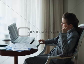Thoughtful business woman working at desk in hotel room