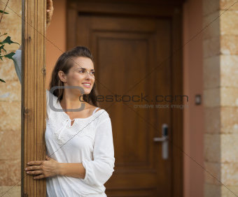 Happy woman standing on doorstep and looking on copy space