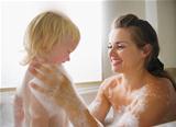 Mother washing with baby in bathtub