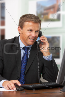 Male Estate Agent Talking On Phone At Desk