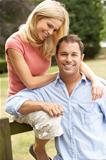 Couple Relaxing In Countryside Sitting On Fence