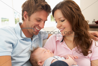 Close Up Of Parents Cuddling Newborn Baby Boy At Home
