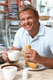 Male Customer Enjoying Sandwich And Coffee In Caf
