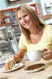 Female Customer Enjoying Slice Of Cake And Coffee In Caf
