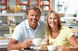 Couple Enjoying Slice Of Cake And Coffee In Caf
