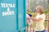 Woman At Recycling Centre Disposing Of Clothing
