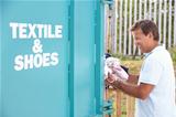 Man At Recycling Centre Disposing Of Clothing