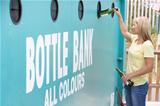 Woman At Recycling Centre Disposing Of Glass At Bottle Bank