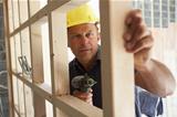 Construction Worker Building Timber Frame In New Home