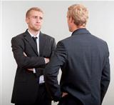 two young businessmen standing, discussing, arguing