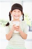 Happy  little girl holding a glass of fresh milk 