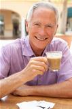 Senior Man Enjoying Coffee And Cake In Caf