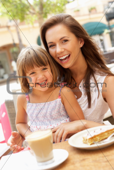 Mother And Daughter Enjoying Cup Of Coffee And Piece Of Cake In Caf