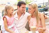 Young Family Enjoying Cup Of Coffee In Caf Together