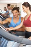 Woman Working With Personal Trainer On Running Machine In Gym