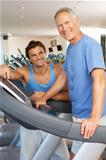 Man Working With Personal Trainer On Running Machine In Gym