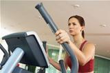 Woman On Cross Trainer Machine In Gym