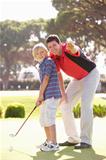 Father Teaching Son To Play Golf On Putting On Green