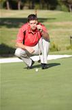 Male Golfer On Golf Course Lining Up Putt On Green