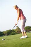 Senior Female Golfer Teeing Off On Golf Course