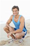 Young Man In Fitness Clothing Resting After Exercise On Beach