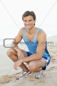 Young Man In Fitness Clothing Resting After Exercise On Beach