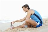 Young Man In Fitness Clothing Stretching On Beach