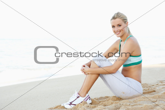 Young Woman In Fitness Clothing Resting After Exercise On Beach