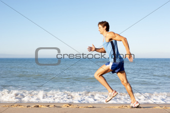 Young Man In Fitness Clothing Running Along Beach