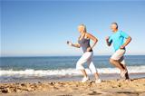 Senior Couple In Fitness Clothing Running Along Beach