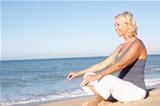 Senior Woman In Fitness Clothing Meditating On Beach