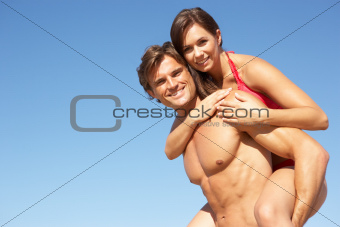 Young Couple Enjoying Piggyback On Beach Holiday