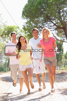 Two young couples, together, running in park
